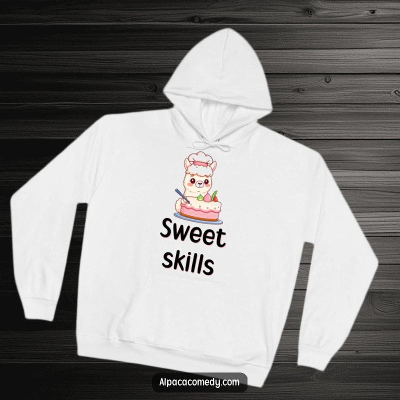 Funny hoodie featuring a skilled alpaca chef in a hat, carefully decorating a charming pastel cake, offering warmth and whimsy.