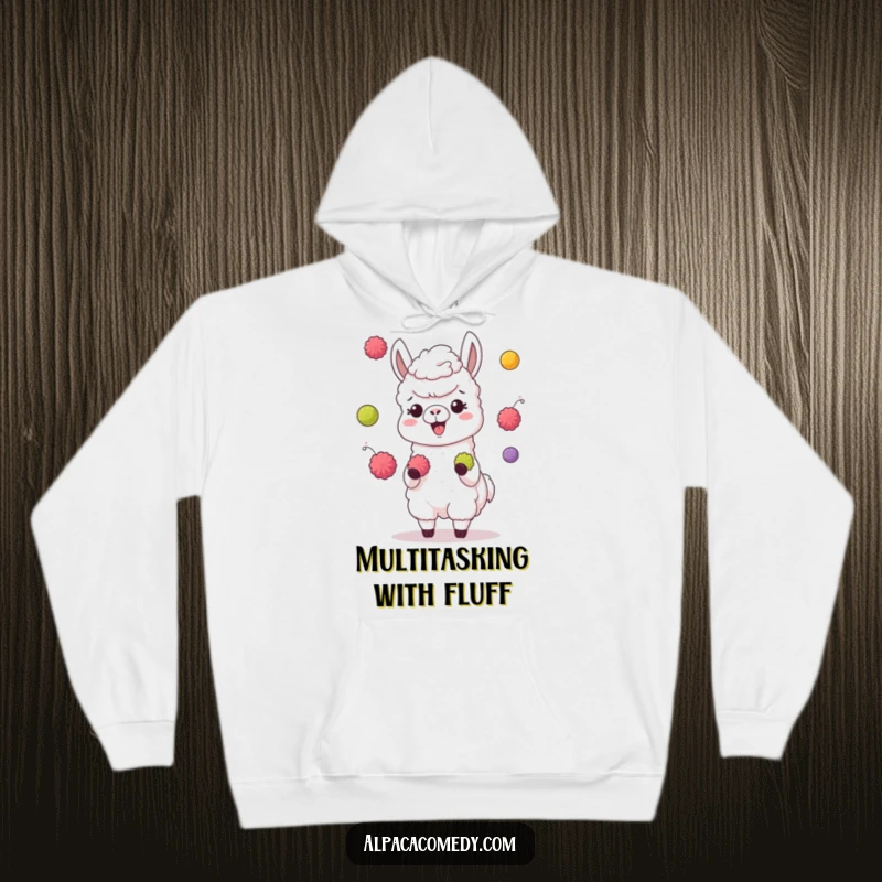 Funny hoodie showing a giggling alpaca character juggling colorful pompoms with its hooves, perfect for cozy, cheerful days.