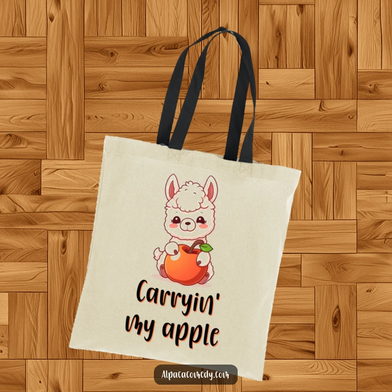 Funny tote bag featuring an alpaca character playfully nudging a rolling apple, showcasing curiosity and a gentle, engaging interaction.